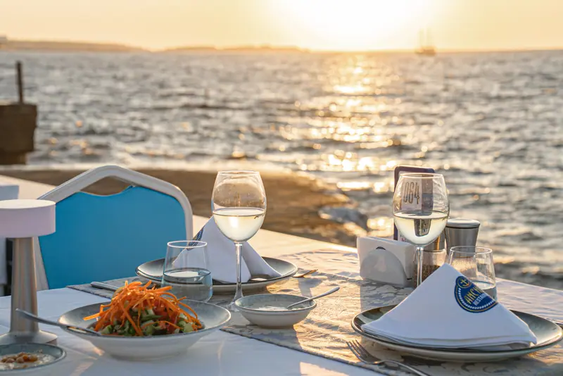 Anchor Restaurant, gün batımında deniz kenarı masa